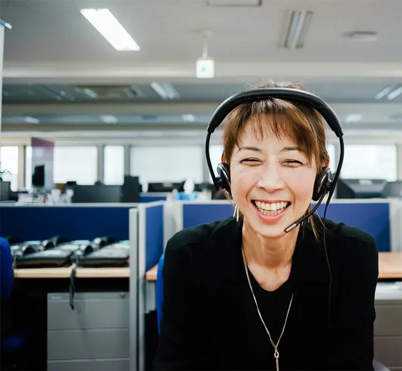 A staff interpreter smiles as she supports a call with a doctor and patient.
